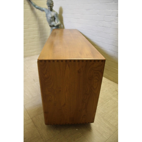 1006 - ERCOL SIDEBOARD a vintage light elm sideboard, with three central drawers flanked by cupboards on ea... 