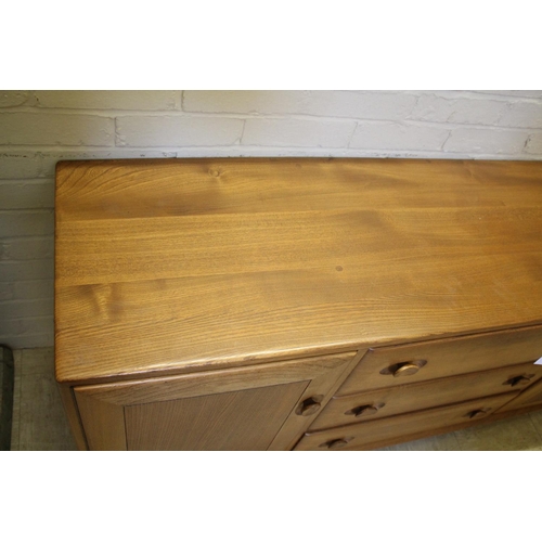 1006 - ERCOL SIDEBOARD a vintage light elm sideboard, with three central drawers flanked by cupboards on ea... 