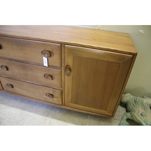 1006 - ERCOL SIDEBOARD a vintage light elm sideboard, with three central drawers flanked by cupboards on ea... 