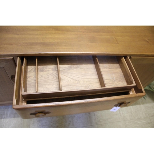 1006 - ERCOL SIDEBOARD a vintage light elm sideboard, with three central drawers flanked by cupboards on ea... 