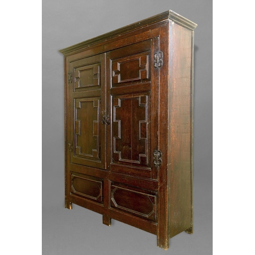 1724 - A CHARLES II STYLE OAK PANELLED CUPBOARD, with a swept moulded cornice above twin doors with geometr... 