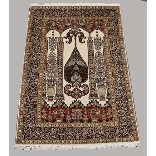 1887 - KASHMIR SILK PILED PRAYER RUG,  modern. The ivory field with triple Mihrab above urns issuing flower... 