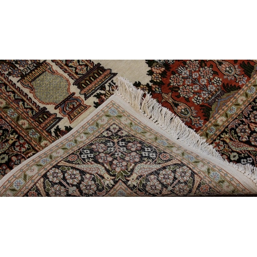 1887 - KASHMIR SILK PILED PRAYER RUG,  modern. The ivory field with triple Mihrab above urns issuing flower... 