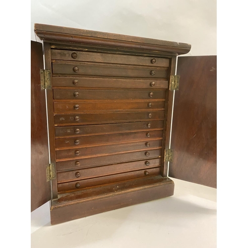 1190 - A TWO DOOR STAINED WOODEN COIN CABINET. The two doors with ebonised stringing, with twelve drawers c... 