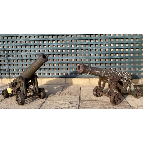 568 - A PAIR OF CAST IRON CANNON ON CARRIAGES. With 95cm long barrels cast with a crown at the pivot point... 