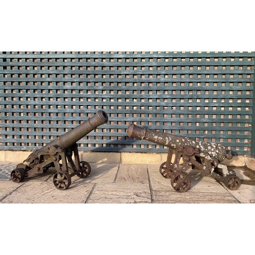 568 - A PAIR OF CAST IRON CANNON ON CARRIAGES. With 95cm long barrels cast with a crown at the pivot point... 