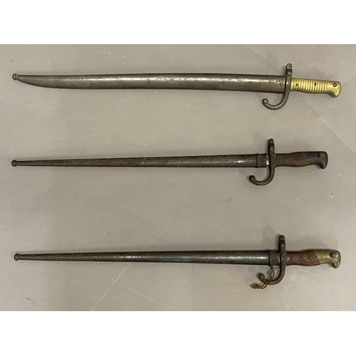 642 - THREE SIMILAR FRENCH SWORD BAYONETS AND SCABBARDS. A French bayonet, with a 52.5cm pointed blade, th... 