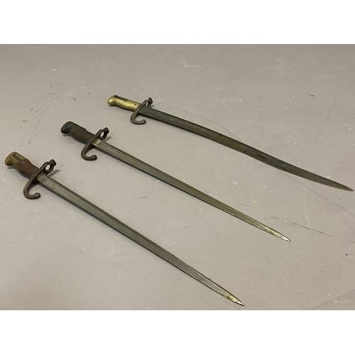 642 - THREE SIMILAR FRENCH SWORD BAYONETS AND SCABBARDS. A French bayonet, with a 52.5cm pointed blade, th... 