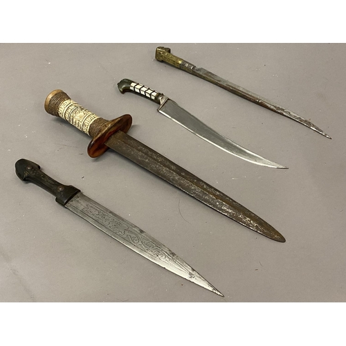 653 - A COLLECTION OF FOUR EASTERN KNIVES AND SCABBARDS. A steel bladed knife with a 25cm tapering pointed... 