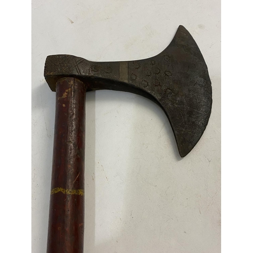 670 - A TRIBAL AXE WITH LONG PAINTED HANDLE. The axe head with a rounded cutting edge and impressed star d... 