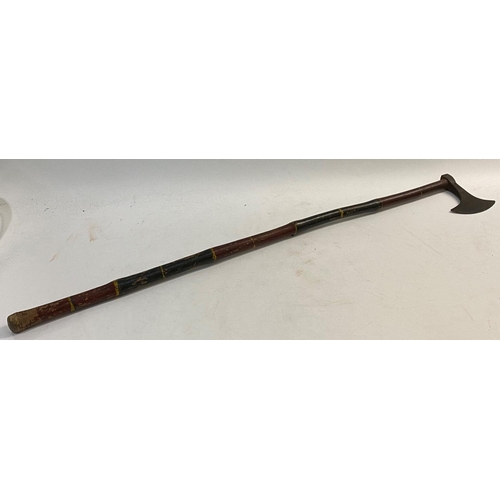 670 - A TRIBAL AXE WITH LONG PAINTED HANDLE. The axe head with a rounded cutting edge and impressed star d... 