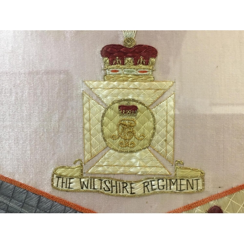 689 - A WILTSHIRE REGIMENT NEEDLEWORK PANEL. A finely worked needlework panel with crossed Colours beneath... 