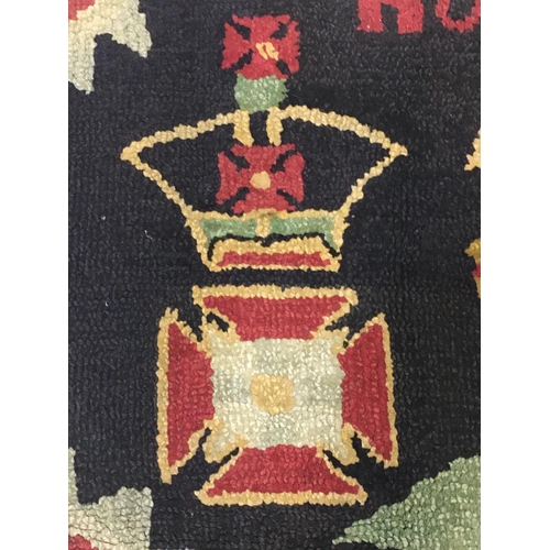 693 - A NAIVE HAND-KNOTTED REGIMENTAL RUG. A rectangular hand knotted woolen rug worked with the motto 'Ho... 