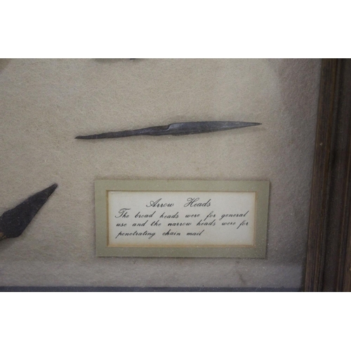 1511 - FRAMED ARROW HEADS a cased display with various metal arrow heads and shafts, with an information la... 