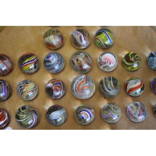 1503 - SOLITAIRE & MARBLES a qty of mostly hand blown latticino core swirl marbles, mounted on a wooden sol... 