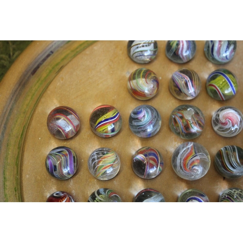 1503 - SOLITAIRE & MARBLES a qty of mostly hand blown latticino core swirl marbles, mounted on a wooden sol... 