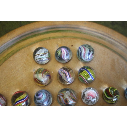 1503 - SOLITAIRE & MARBLES a qty of mostly hand blown latticino core swirl marbles, mounted on a wooden sol... 