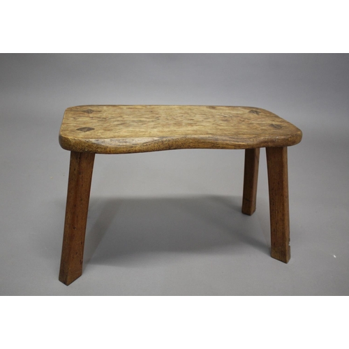 872 - GNOMEMAN OAK STOOL - THOMAS WHITTAKER (1910-1991) a large adzed stool with a shaped oak top, support... 