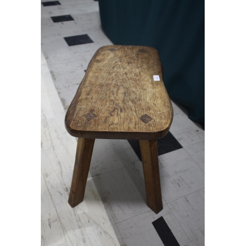 872 - GNOMEMAN OAK STOOL - THOMAS WHITTAKER (1910-1991) a large adzed stool with a shaped oak top, support... 