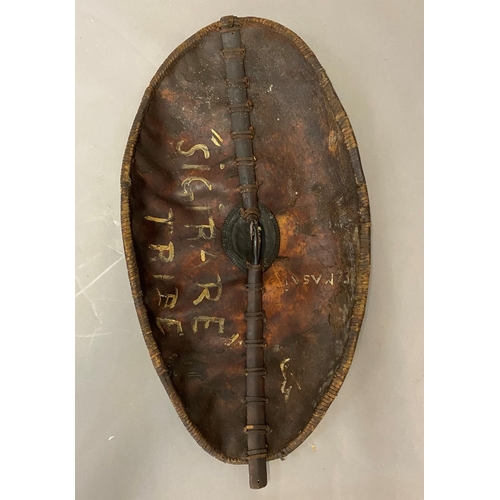 673 - A 19TH CENTURY MASSI WARRIORS HIDE SHIELD. A large hide shield of domed oval form with bound border ... 