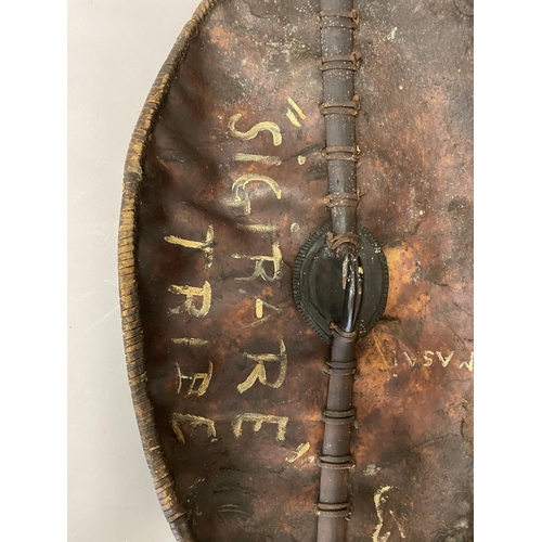 673 - A 19TH CENTURY MASSI WARRIORS HIDE SHIELD. A large hide shield of domed oval form with bound border ... 