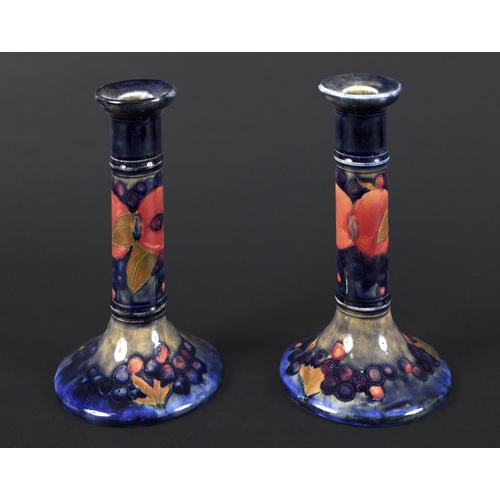 729 - PAIR OF MOORCROFT CANDLESTICKS - POMEGRANATE a pair of William Moorcroft candlesticks, in the Pomegr... 