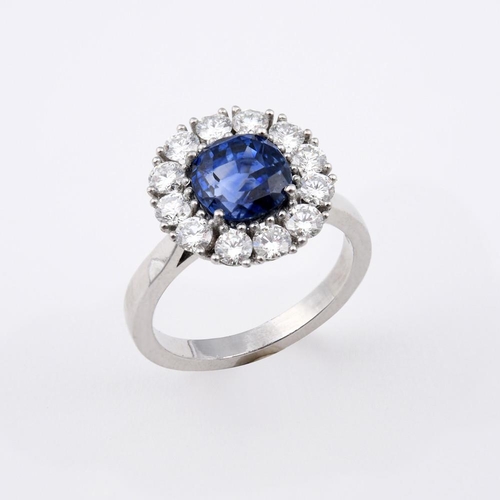 1175 - A SAPPHIRE AND DIAMOND CLUSTER RING. the cushion-shaped sapphire weighs 3.94 carats and is set withi... 