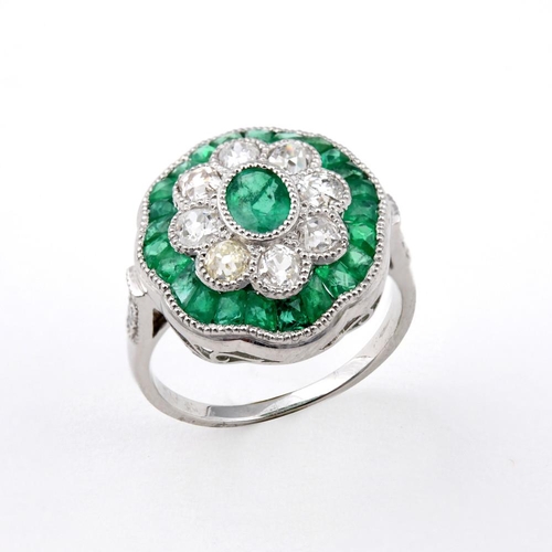 1176 - AN EMERALD AND DIAMOND CLUSTER RING. the central oval-shaped emerald is set within a surround of eig... 