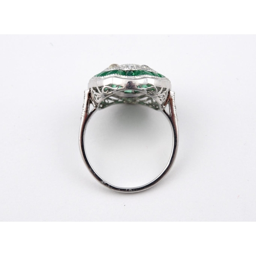 1176 - AN EMERALD AND DIAMOND CLUSTER RING. the central oval-shaped emerald is set within a surround of eig... 