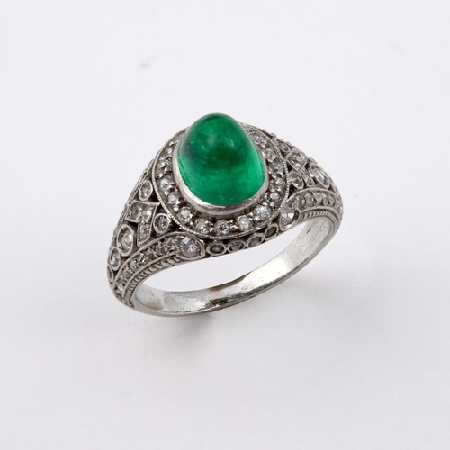 1177 - AN EMERALD & DIAMOND CLUSTER RING. the oval-shaped cabochon emerald is set within a surround of circ... 