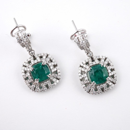 1186 - A PAIR OF EMERALD AND DIAMOND DROP EARRINGS. each set with a cushion-shaped emerald within an openwo... 