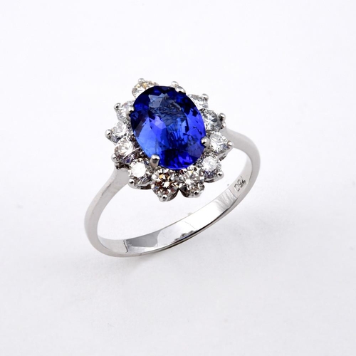 1187 - A TANZANITE AND DIAMOND CLUSTER RING. the oval-shaped tanzanite weighs 1.71 carats and is set within... 