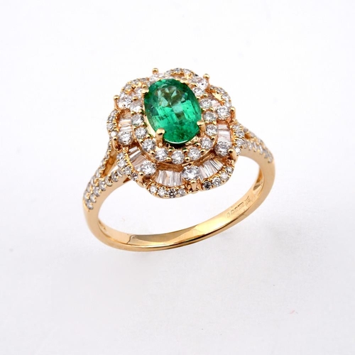 1188 - AN EMERALD AND DIAMOND CLUSTER RING. the oval-shaped emerald is set within a surround of round brill... 