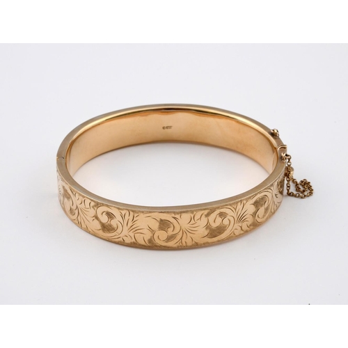 951 - A 9CT GOLD HALF HINGED BANGLE. with foliate engraved decoration to one side, internal measurements 6... 