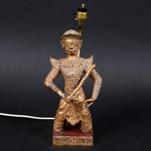 899 - SOUTH EAST ASIAN GILT METAL FIGURAL LAMP. A gilt metal figure with elaborate clothing, crouched on i... 