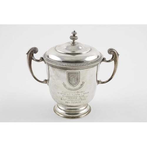 157 - A GEORGE V TWO-HANDLED CUP AND COVER. the domed cover with a fluted finial, the body with  scroll ha... 