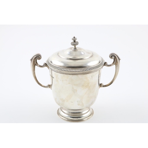 157 - A GEORGE V TWO-HANDLED CUP AND COVER. the domed cover with a fluted finial, the body with  scroll ha... 