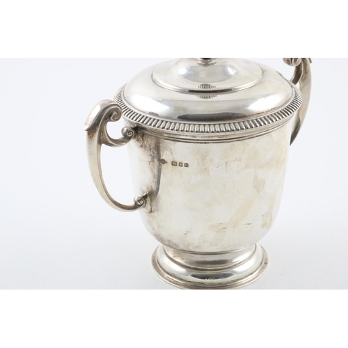 157 - A GEORGE V TWO-HANDLED CUP AND COVER. the domed cover with a fluted finial, the body with  scroll ha... 