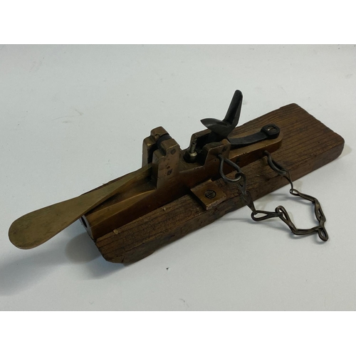 29 - A PERCUSSION FIRING ALARM GUN. A Brass Percussion cap firing alarm gun mounted on a wood base, the p... 