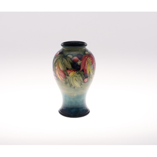 694 - MOORCROFT VASE - LEAF & BERRY. An early Moorcroft vase in the Leaf and Berry design on green and blu... 