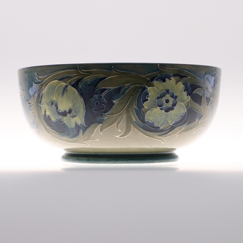 696 - ANTIQUE MOORCROFT BOWL - LATE FLORIAN. A large bowl painted with flowers and leaves on a blue and gr... 