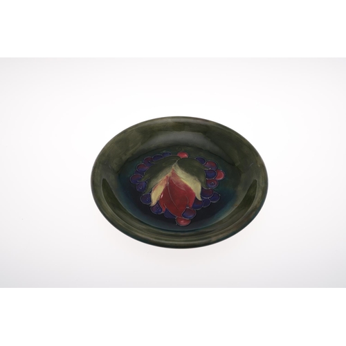 697 - ANTIQUE MOORCROFT PLATE - LEAF & BERRY, ORIGINAL PAPER LABEL. The plate painted in the centre with a... 