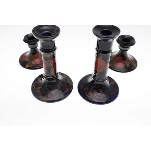 721 - TWO PAIRS OF ANTIQUE MOORCROFT CANDLESTICKS - POMEGRANATE. Including a small pair of candlesticks, p... 