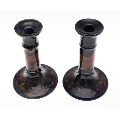 721 - TWO PAIRS OF ANTIQUE MOORCROFT CANDLESTICKS - POMEGRANATE. Including a small pair of candlesticks, p... 