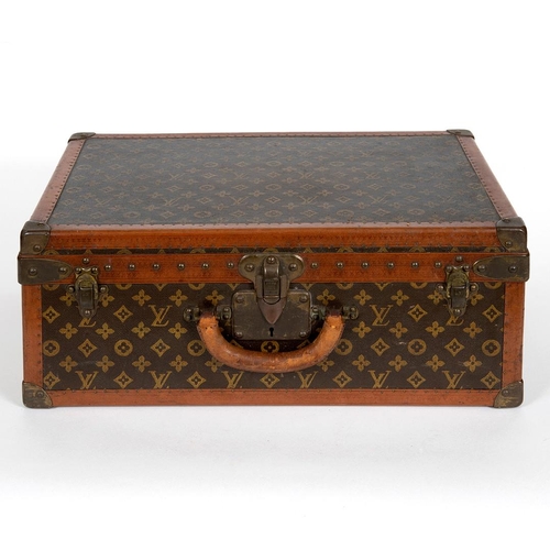 573 - VINTAGE LOUIS VUITTON SUITCASE. With a monogrammed exterior, leather trim with brass studs and brass... 