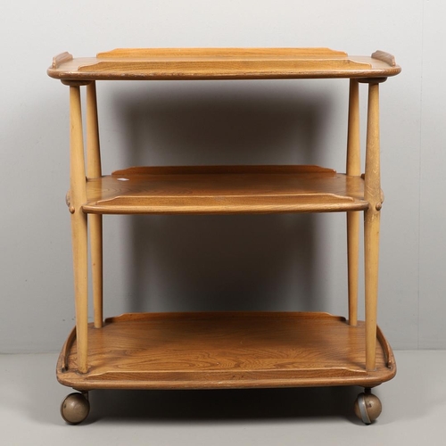 668 - ERCOL TEA TROLLEY & PLATE RACK. A three tier light elm and beech tea trolley, raised on roller casto... 