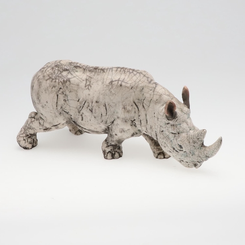 713 - LARGE RAKU POTTERY RHINO. A large raku model of a Rhino, in a standing position with head near the g... 