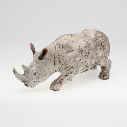 713 - LARGE RAKU POTTERY RHINO. A large raku model of a Rhino, in a standing position with head near the g... 