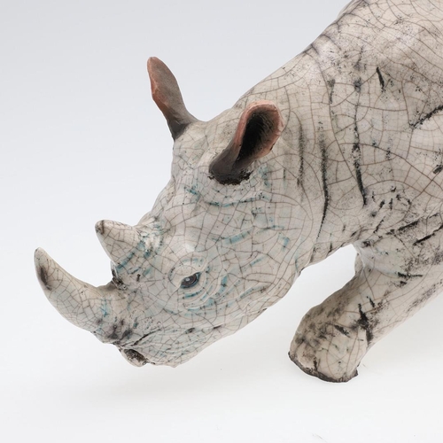 713 - LARGE RAKU POTTERY RHINO. A large raku model of a Rhino, in a standing position with head near the g... 