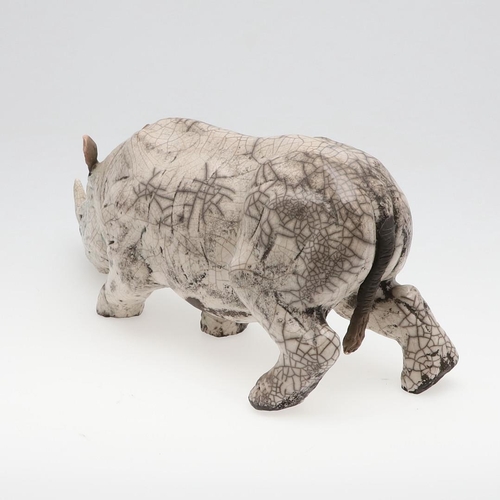 713 - LARGE RAKU POTTERY RHINO. A large raku model of a Rhino, in a standing position with head near the g... 